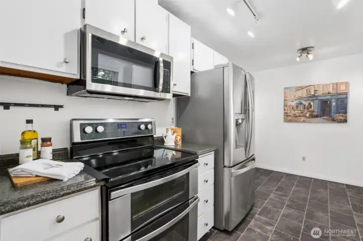 Bright, updated kitchen with white cabinetry, stainless-steel appliances, generous storage, and easy-care tile flooring.