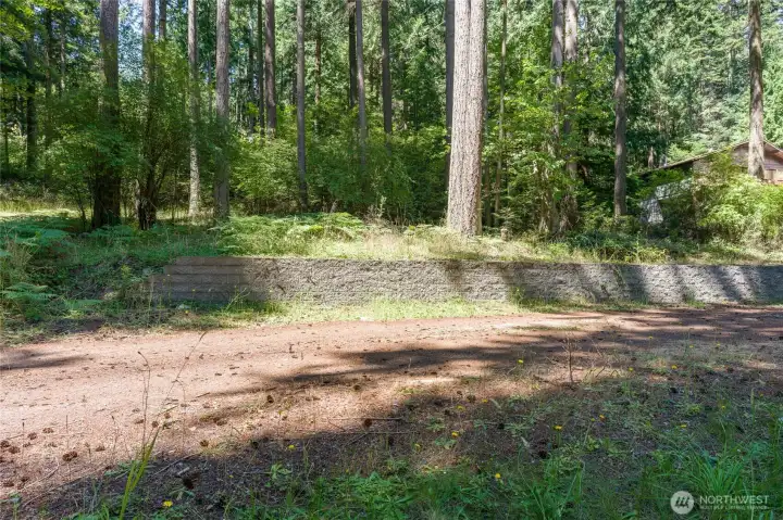 A retaining wall provides a level space to unwind and take in filtered views of Mud Bay, mature evergreens, wildlife, and a tranquil forest setting A retaining wall provides a level space to unwind and take in filtered views of Mud Bay, mature evergreens, wildlife, and a tranquil forest setting