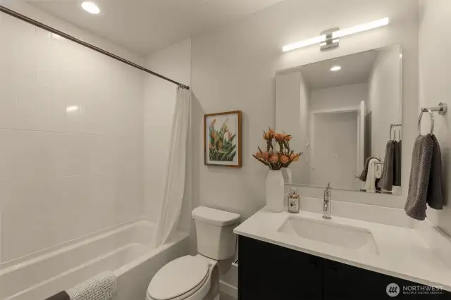 Modern bathroom featuring a sleek vanity, spacious mirror, and full bathtub with classic tile surround – a serene retreat for relaxation.