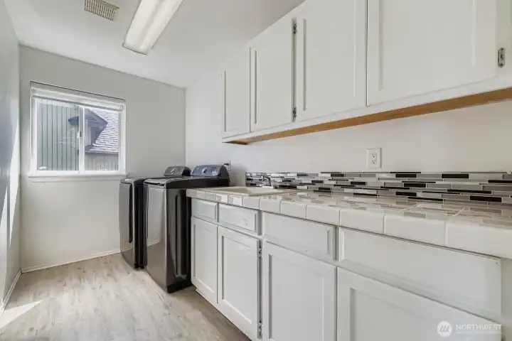 Laundry day just got an upgrade, this spacious room features a sink, generous counter space, and plenty of storage