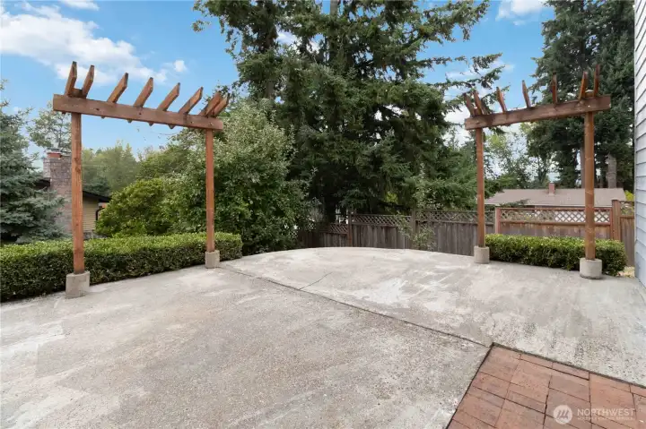 Expansive patio framed by dual pergola accents and mature greenery.