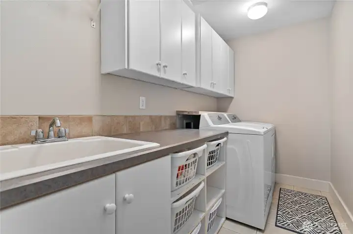 Handy upper level utility room with sink, additional storage, and folding area.