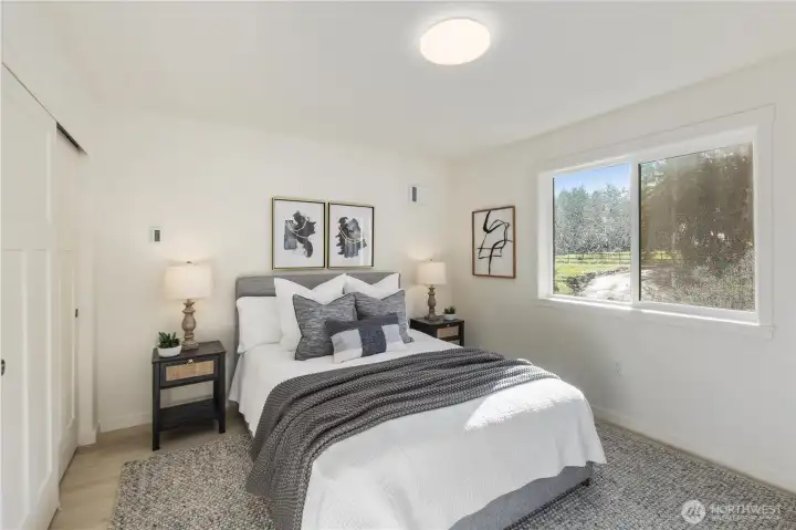 Upper-level bedroom with large window, natural light, and clean modern finishes consistent with new construction design.