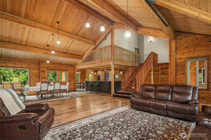 Open concept main floor living area showcasing seamless flow between living room, dining area and kitchen with access to upstairs.