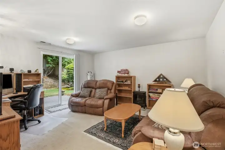 Lower level features a versatile living area with a sliding glass door providing direct access to the backyard patio. This floor also includes a convenient half bathroom and a shared laundry room with additional built-in storage space. Lower level features a versatile living area with a sliding glass door providing direct access to the backyard patio. This floor also includes a convenient half bathroom and a shared laundry room with additional built-in storage space.