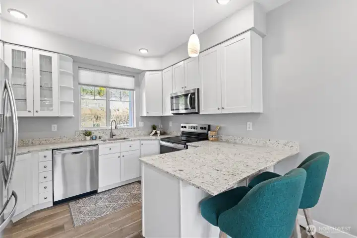 Beautiful kitchen complete with soft close wood cabinetry, stainless steel appliances, and bar seating.