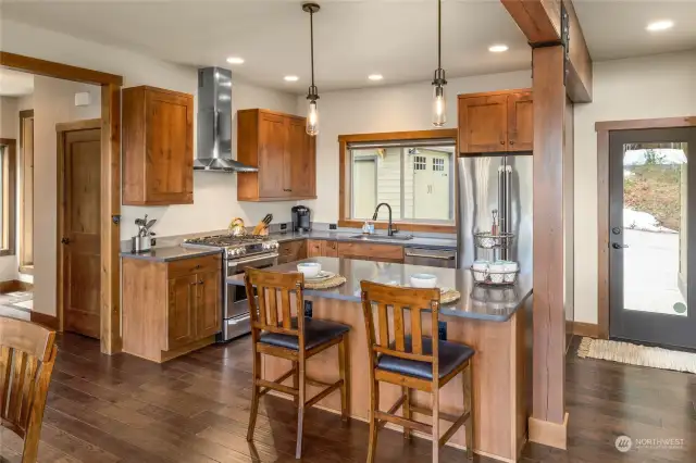 Kitchen features stainless appliances and quartz counters. A secondary entrance to the home is provided by the full light door off the kitchen, a walk-in pantry sits to the right of that door.