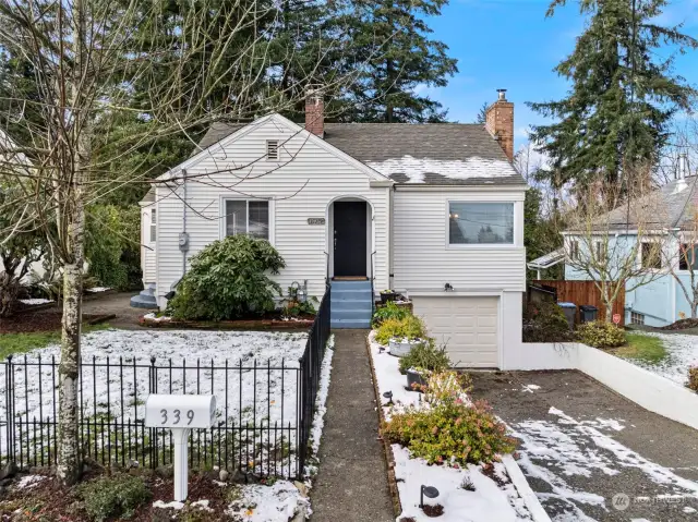 Exterior front with partially fenced yard, walkway and arched doorway.