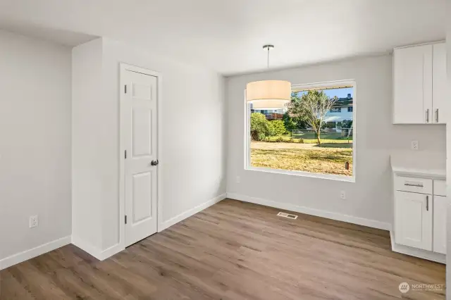 Dining Area with hanging lamp shining out to backyard through the center piece bay window