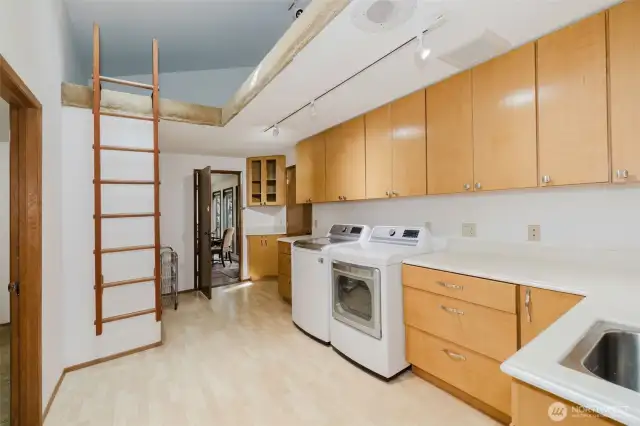 One of two thoughtfully-designed laundry rooms, this space features built-in functionality and a charming ladder leading to a versatile loft—blending practicality with a touch of character.