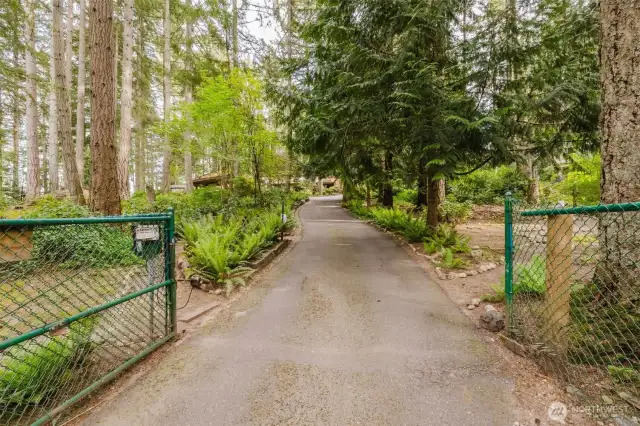 Step through the inviting open gate and discover a serene, park-like retreat surrounded by lush trees and vibrant foliage—a truly tranquil entrance to your future home!