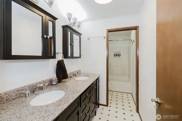 This bathroom includes polished granite countertops, dual sinks, and contemporary mirrors, offering a clean, streamlined look.