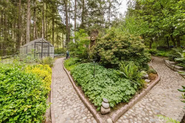 Charming cobblestone paths wind through the backyard, leading you on a delightful journey through a beautiful landscape of enchantment!