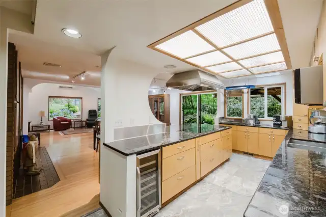 The open kitchen features an industrial cooktop/hood, granite counters, and a wine fridge!