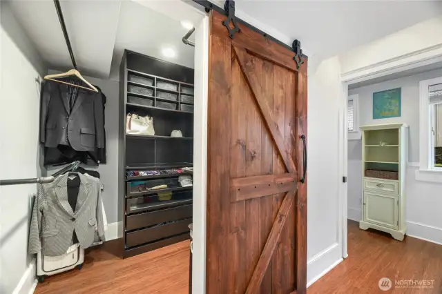 Walk-in Closet for primary suite features huge wood sliding door and built-in shelves and sliding drawers.