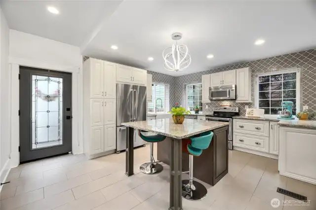 Step inside to be greeted by this luxury kitchen with granite counters, a large island with seating and storage, stainless steel appliances, seperate beverage refrigerator and arabesque tile that extends to the ceiling.