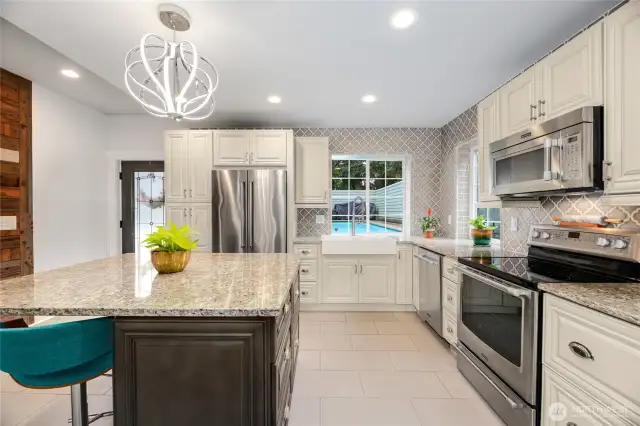 Enjoy a view of the pool while standing in front of the farmhouse sink in this luxury kitchen. Updated with granite counters, a large island with seating and storage, stainless steel appliances, seperate beverage refrigerator, updated lighting.