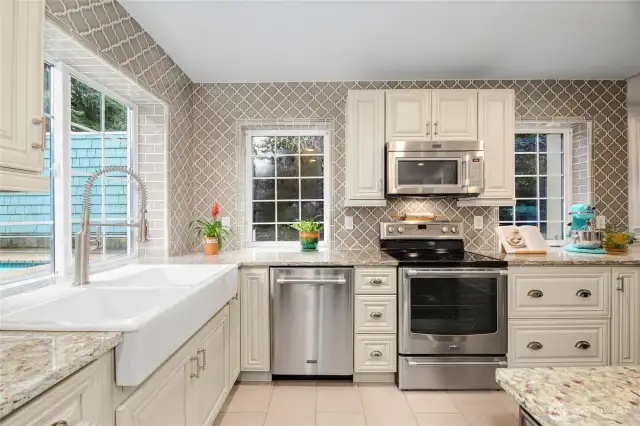 This luxury kitchen greets you with granite counters, a large island with seating and storage, stainless steel appliances, Farmhouse sink, & seperate beverage refrigerator.  Easy to maintenance with tile that extends up to the ceiling.