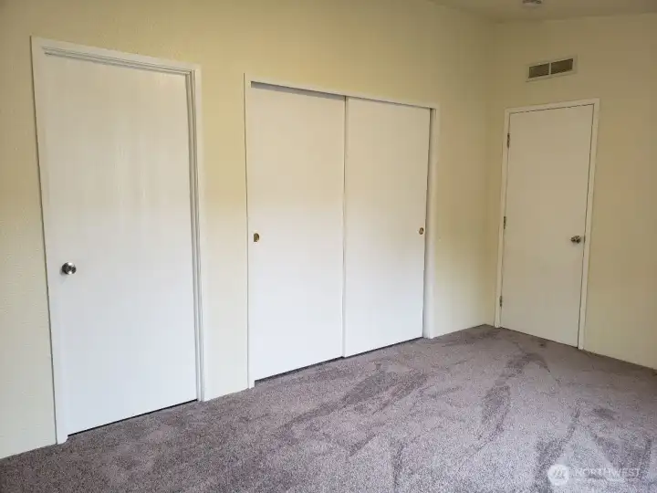 Another Look at the Spacious Primary Master Bedroom with Vaulted Ceiling and Newer Interior Paint and Carpet showing doors to Huge Closet and Full Bath Room.