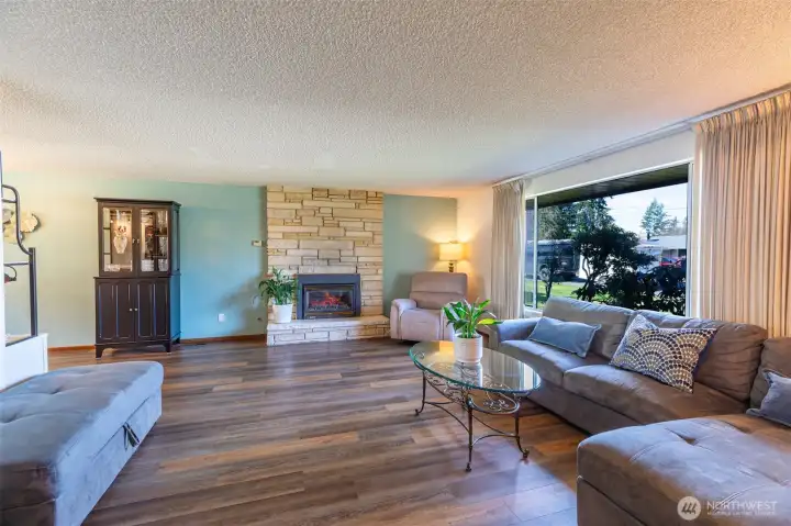 Bright, spacious living room with fireplace, stone mantel & beautiful floors