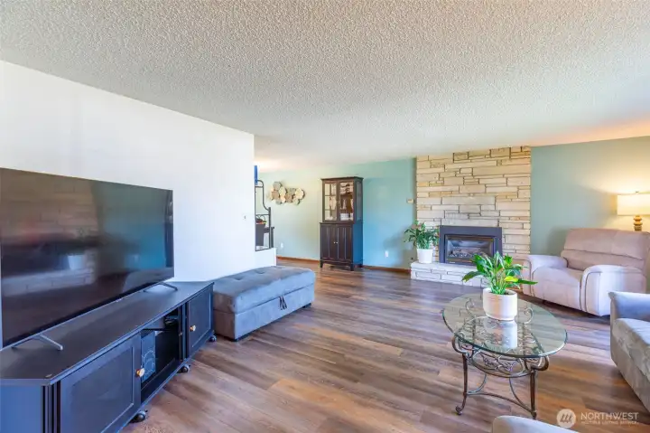 Bright, spacious living room with fireplace, stone mantel & beautiful floors
