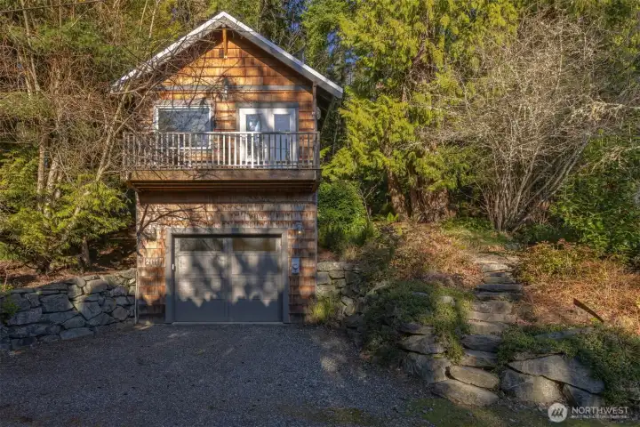Looking at the “cottage” nestled in the evergreens with the natural stone walkway up to the door on the backside of the home.