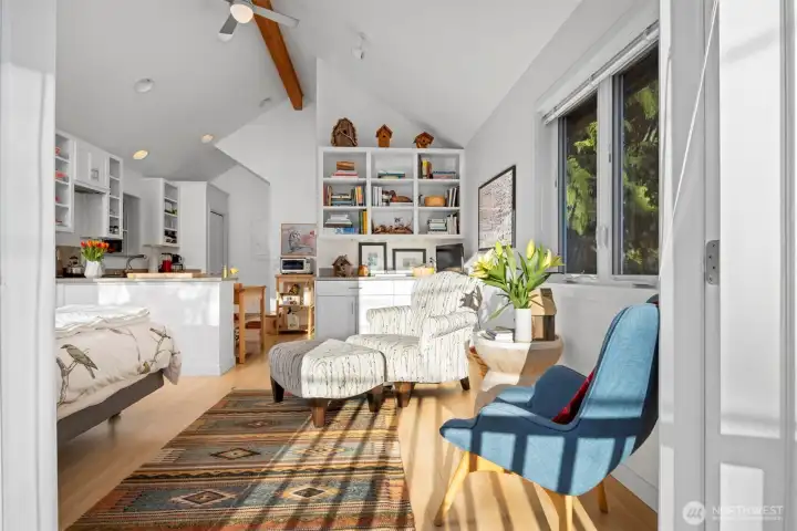 Looking across the living area with the built-ins beyond and the kitchen to the left beyond the bed.