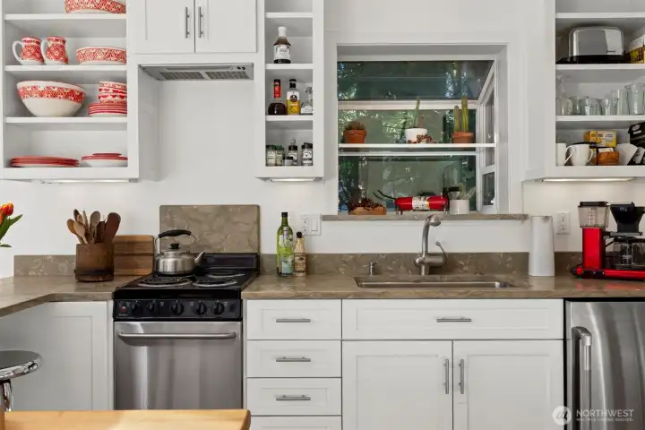 There is a small refrigerator to the right of the sink and a 4-burner stove to the left.