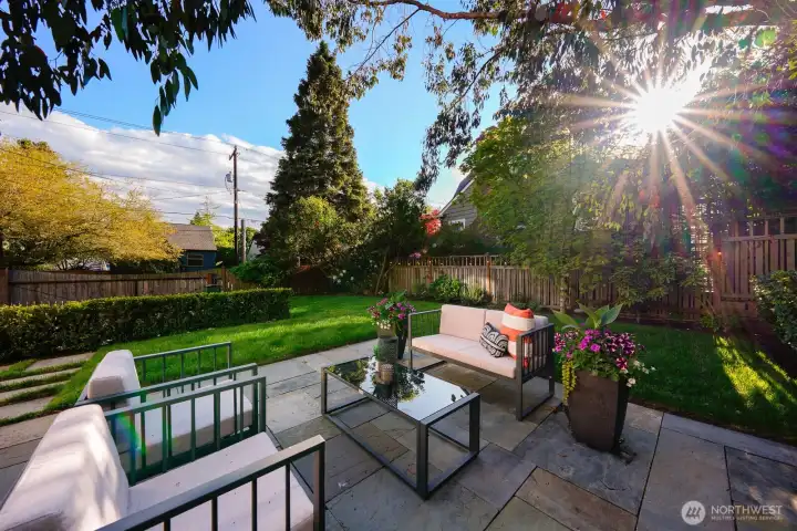 Beautifully landscaped yard with patio and gated driveway.