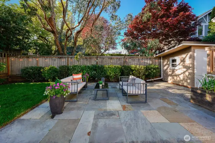 Beautifully landscaped yard with patio and gated driveway.