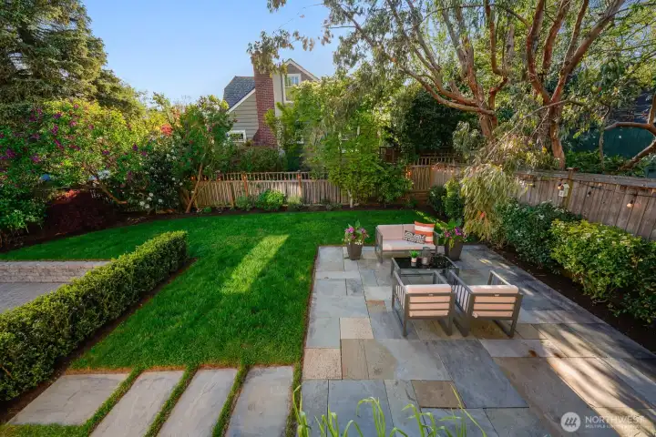 Beautifully landscaped yard with patio and gated driveway.