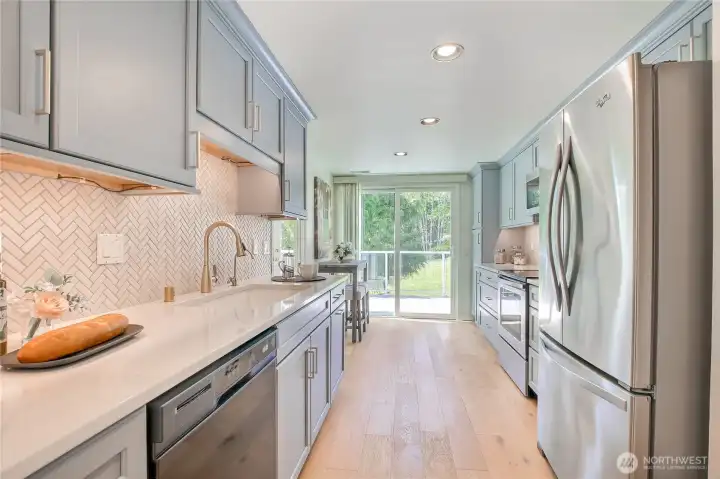 Spacious custom designed kitchen with extended cabinets opens to nook and slider to sunny deck.