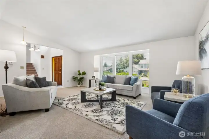 A wall of picture windows fills the living room with natural light, highlighting the spacious layout and comfortable gathering areas.