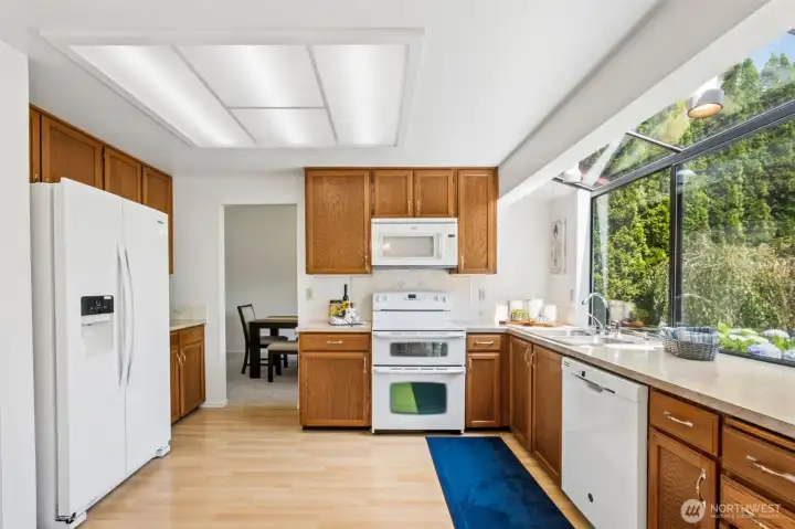 The spacious kitchen offers abundant cabinetry, generous counter space, and a large picture window above the sink that frames peaceful backyard views and fills the room with natural light.