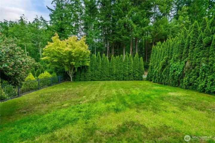 Rimmed with trees and a fence.