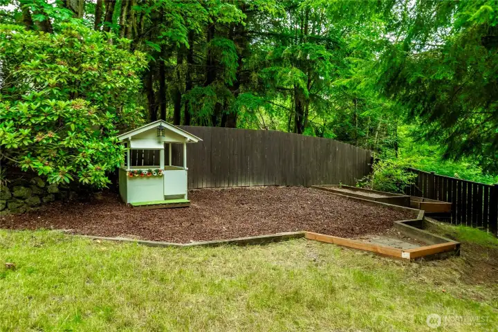 Back side yard with rubber mulch and a playhouse.