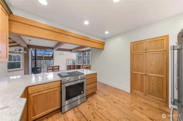 Open-concept kitchen and living area featuring high ceilings with exposed wooden beams.