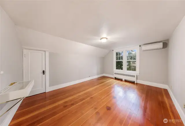 Bedroom with wood flooring and neutral tones, featuring large windows and natural light.