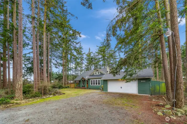 Framed by towering evergreens, this driveway leads you to a home where nature meets modern living. The spacious yard and detached garage create an inviting entry point for a lifestyle centered on outdoor adventures and peaceful retreats, all within the privacy of your own wooded haven.