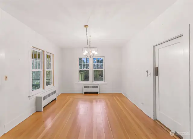 The dining room offers a bright and inviting space, featuring large windows that frame serene outdoor views. With its classic chandelier and hardwood floors, this room provides the perfect setting for intimate meals or lively dinner gatherings. The adjacent kitchen offers easy access for effortless entertaining.