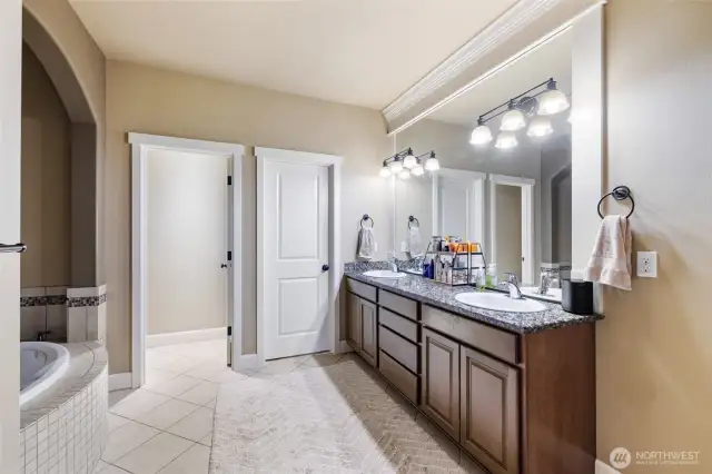 The ensuite bath has a dual vanity, soaking tub, spacious walk-in closet, and tile flooring.