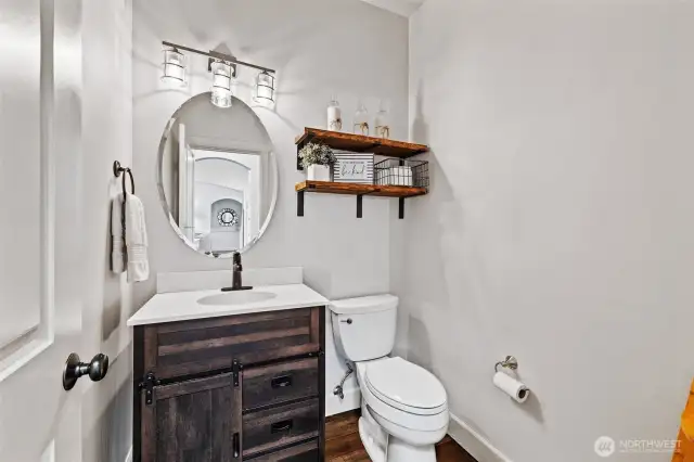 Convenient for guests, the main floor powder room has a roomy vanity, hardwood floors, and modern lighting.