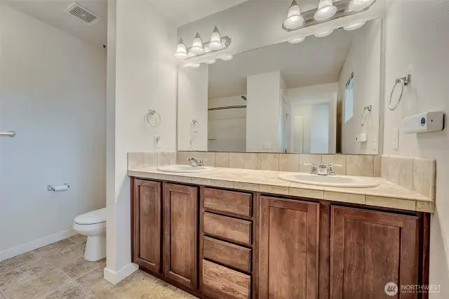 Private master bedroom bath with tiled double vanity, one piece tub surround and a linen closet.
