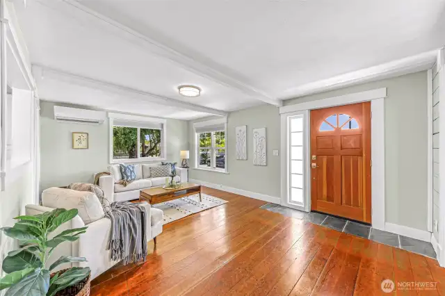 Bright living room with original and reclaimed wide board fir floors, large newer windows and beautiful wood front door.