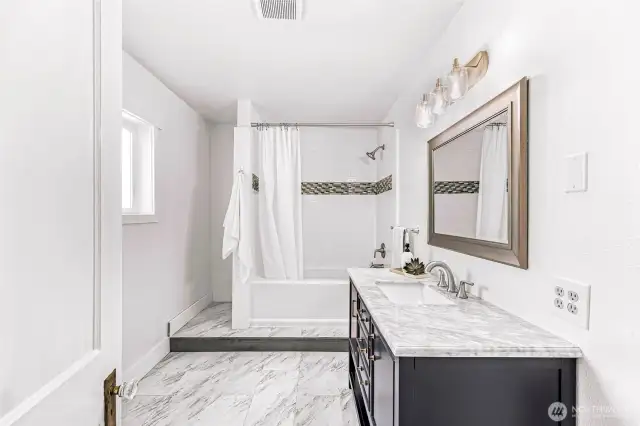 Main floor bathroom off of primary bedroom. Large space with new vanity, tub, and toilet.