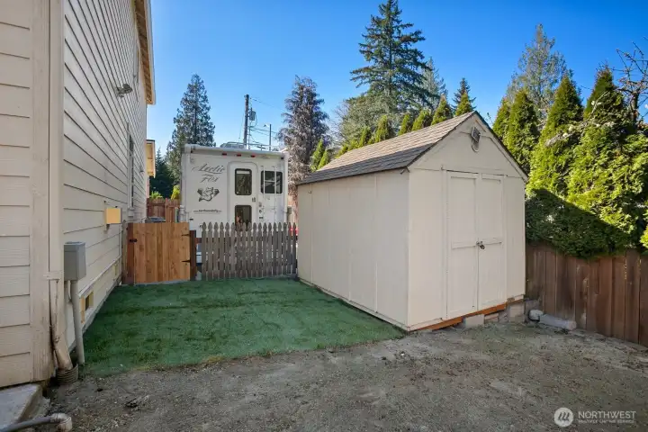 Side of house / backyard showing storage shed, area for potential gardening, and RV or boat parking area.  Rubbermaid storage container & carport tent (both not visible in photo) convey with sale.