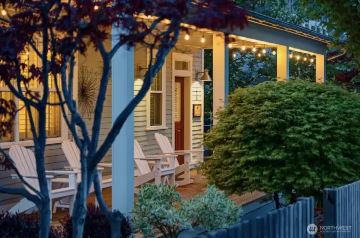 Exterior twilight view of home with classic covered front porch and mature landscaping.