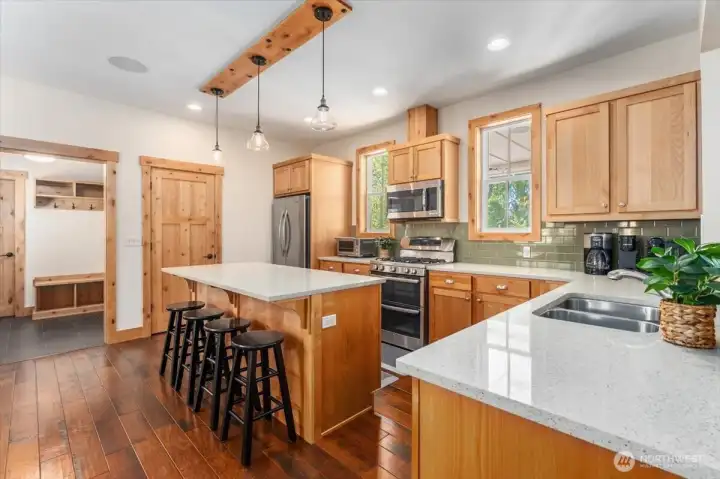 View 2 of kitchen with quartz countertops and stainless steel appliances and sit up bar.