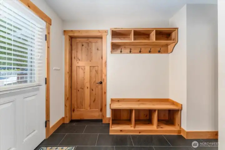 View of entryway with built-in storage cabinets looking towards door to 2-car garage.