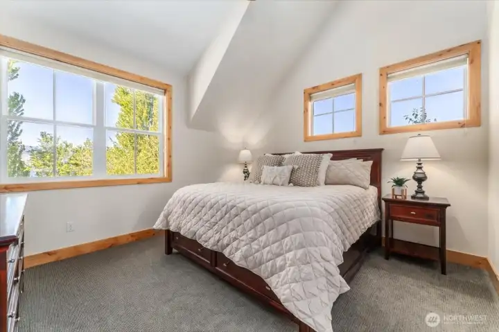 View 1 of upper level Primary Bedroom with King bed, oversized windows, walk-in closet and en-suite full bathroom.